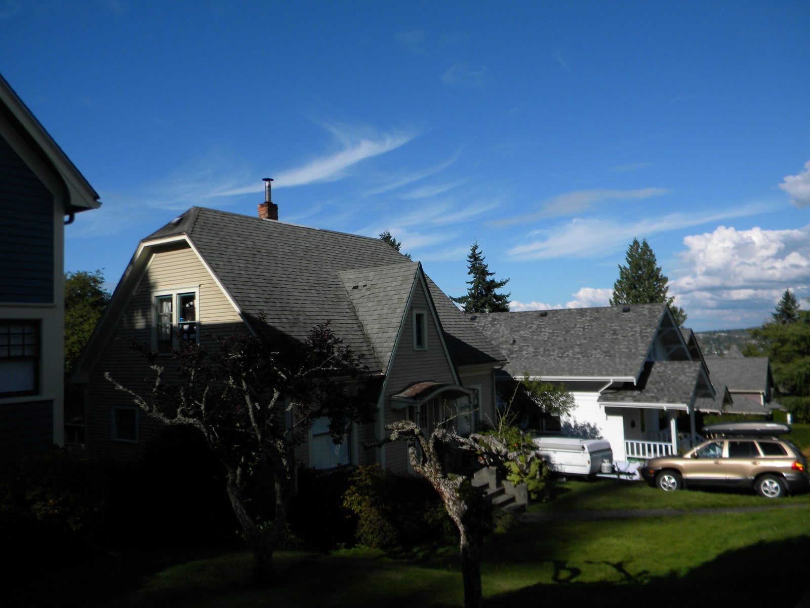 Gray gabled house with a front garden in the Sehome Hill Historic District, with neighboring homes and the bay in the distance